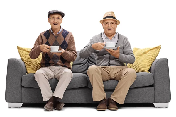 Χαρούμενη ηλικιωμένους με κύπελλα κάθεται σε έναν καναπέ — Φωτογραφία Αρχείου