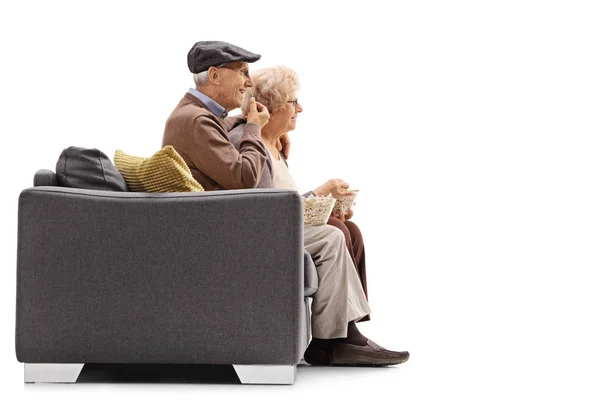 Homem e mulher sentados em um sofá e comer pipocas — Fotografia de Stock