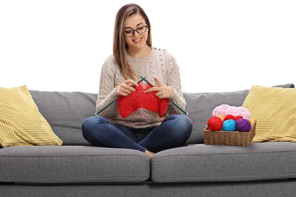 Mujer feliz sentada en un sofá y tejiendo — Foto de Stock