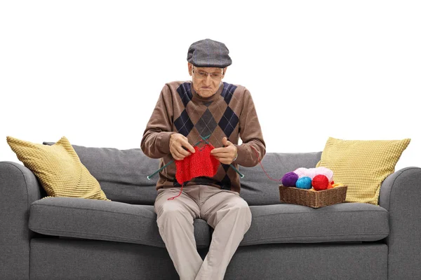 Clueless senior sitting on a sofa and knitting — Stock Photo, Image