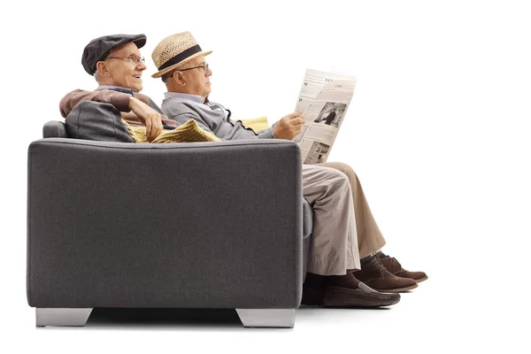 Hommes assis sur un canapé avec l'un d'eux lisant un journal — Photo