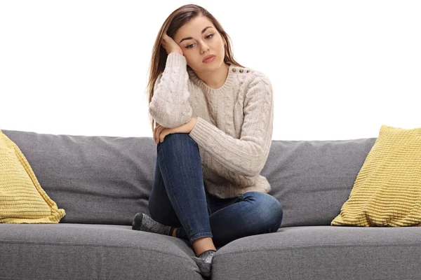 Sad young woman sitting on a sofa — Stock Photo, Image