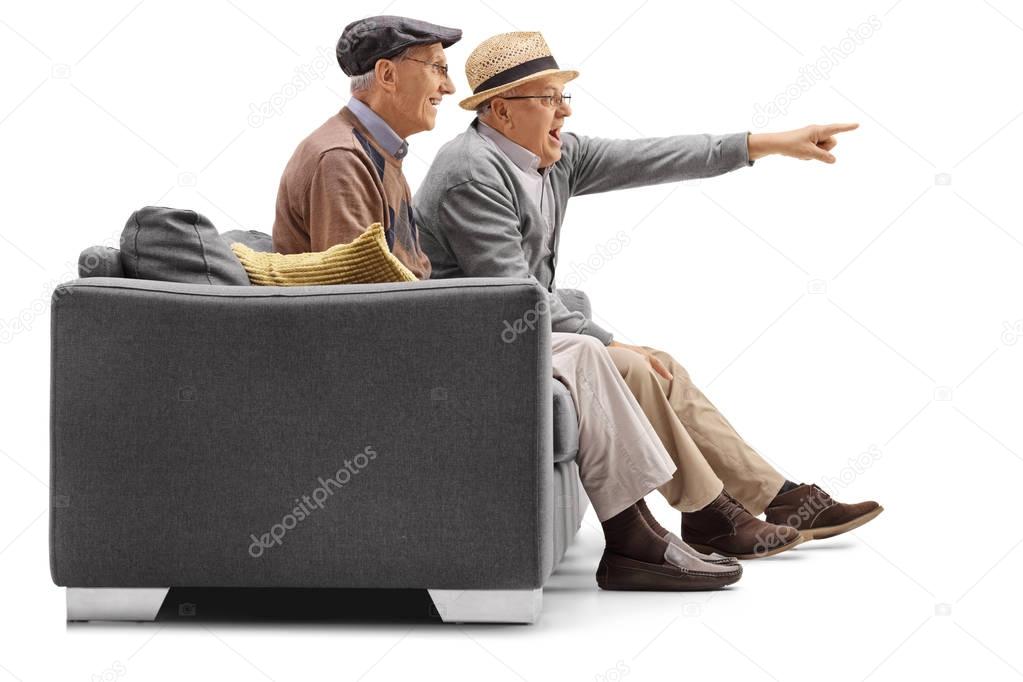 mature men sitting on a couch with one of them pointing