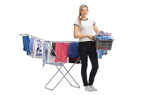 Kvinna som håller tvättkorg framför kläder rack torktumlare — Stockfoto