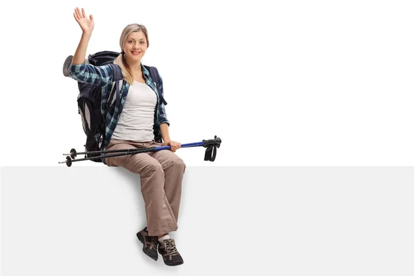 Female hiker sitting on a panel and waving — Stock Photo, Image