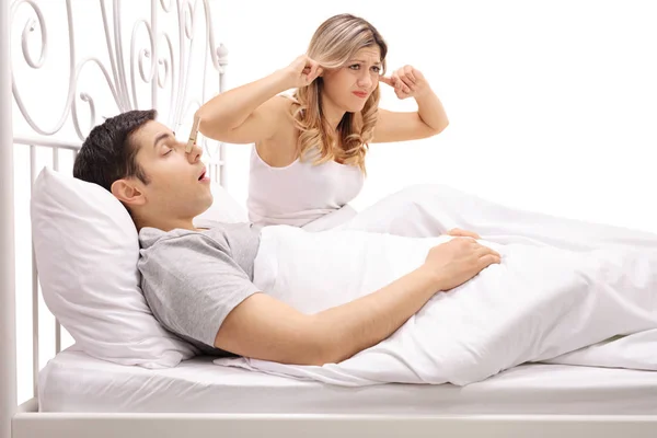 Homem dormindo e roncando ao lado de mulher batendo seus ouvidos — Fotografia de Stock