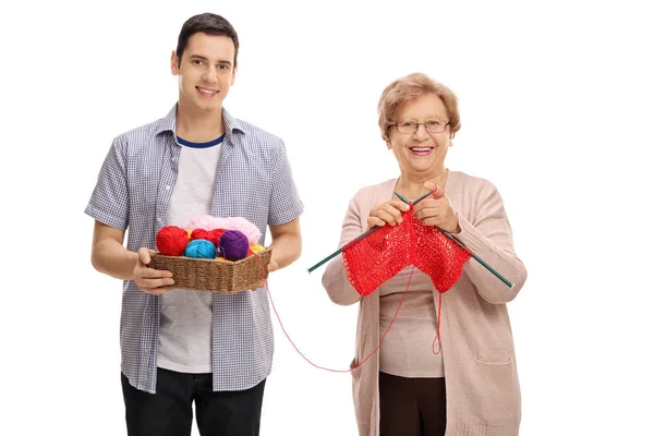 Young man helping a mature lady knit — Stock Photo, Image