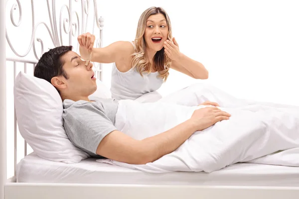 Man snurken naast een vrouw een wasknijper op zijn neus zetten — Stockfoto