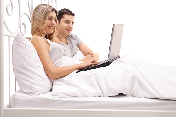 Pasangan berbaring di tempat tidur dan melihat laptop — Stok Foto