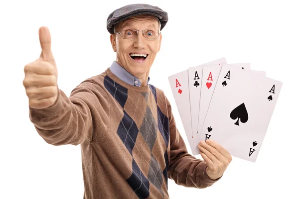 Overjoyed senior holding four aces and making a thumb up — Stock Photo, Image