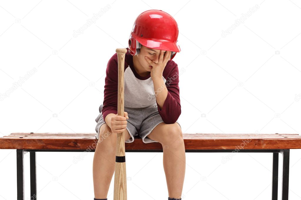 Sad kid with baseball bat holding his head in disbelief