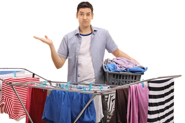 Guy holding laundry basket behind clothing rack dryer — Stock Photo, Image