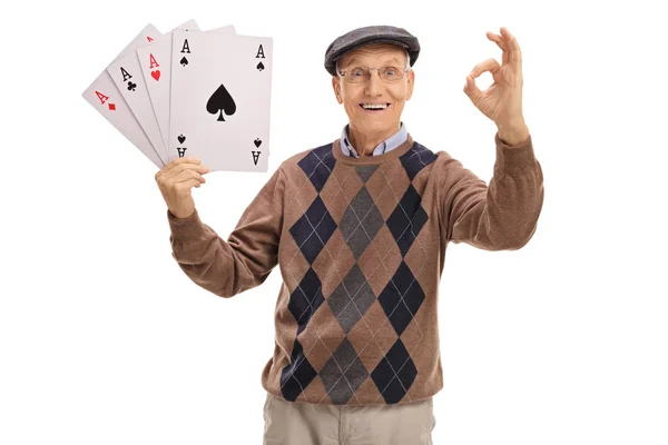 Cheerful senior holding aces and making an ok sign — Stock Photo, Image