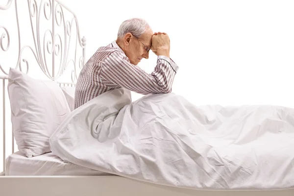 Депрессивный старший лежит в постели с опущенной головой — стоковое фото