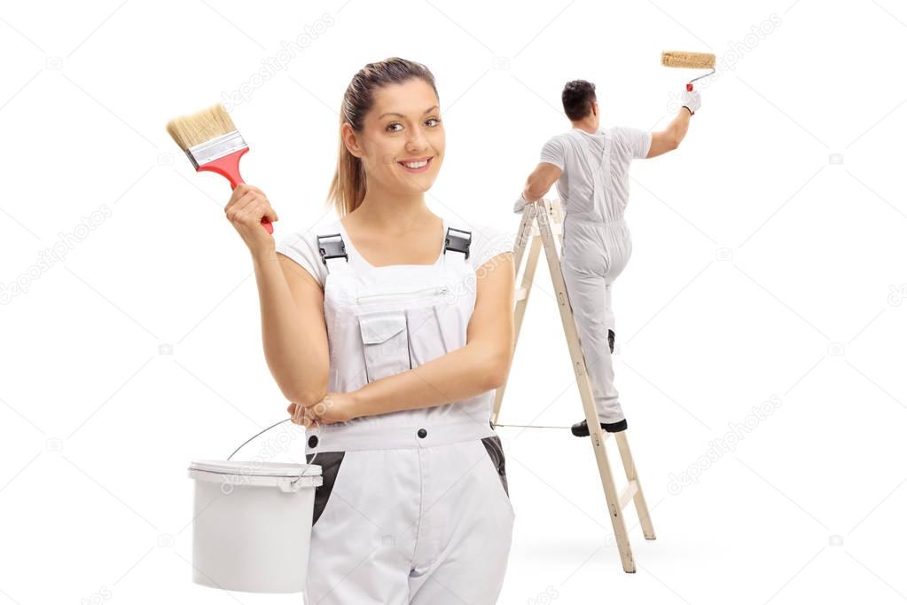 Female painter with male painter painting climbed up a ladder