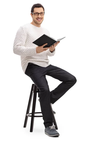 Cara alegre com um livro sentado em uma cadeira — Fotografia de Stock