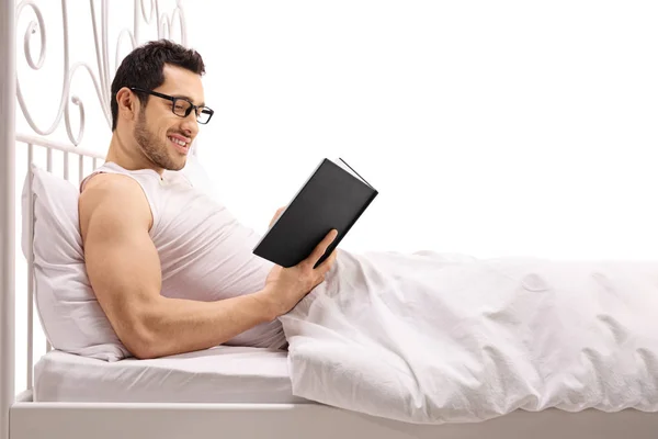 Ο άνθρωπος ξαπλωμένος στο κρεβάτι και διαβάζοντας ένα βιβλίο — Φωτογραφία Αρχείου