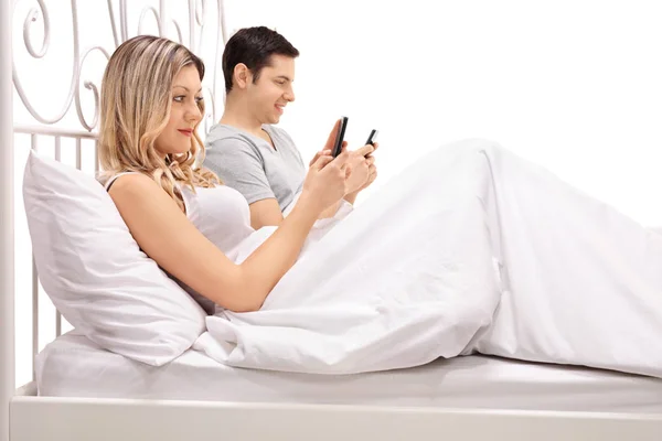 Paar liegt im Bett und schaut auf sein Handy — Stockfoto