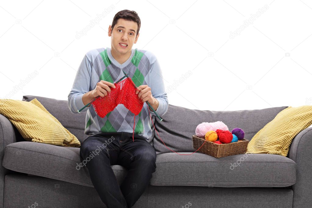 Confused young man attempting to knit