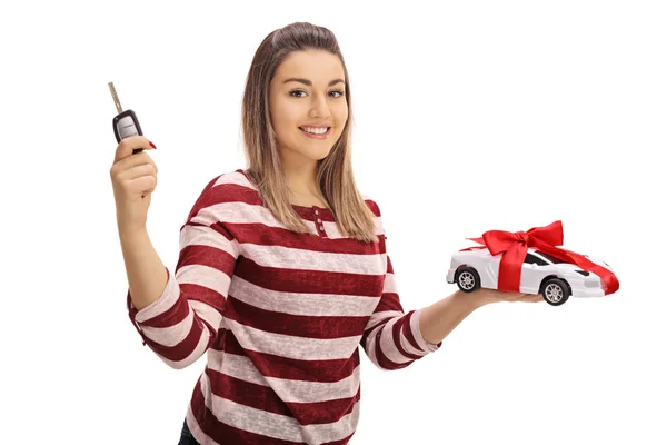 Mulher segurando uma chave de carro e um carro modelo — Fotografia de Stock