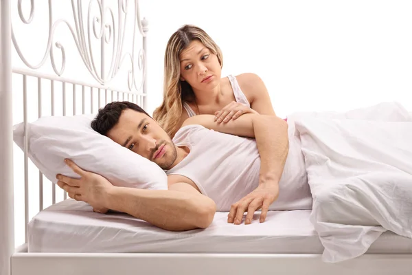 Uomo infelice sdraiato a letto con donna preoccupata che lo conforta — Foto Stock