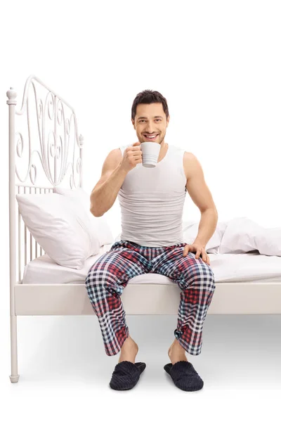 Man sitting on bed and drinking from cup — Stock Photo, Image