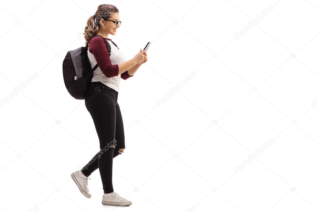 Female student walking and looking at mobile phone