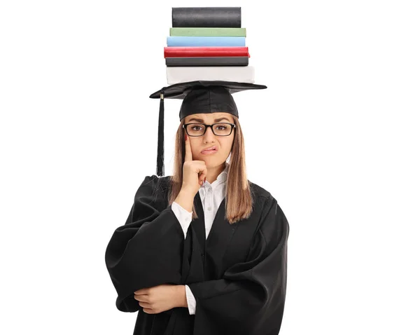 Enojada estudiante de posgrado con un montón de libros en su cabeza — Foto de Stock
