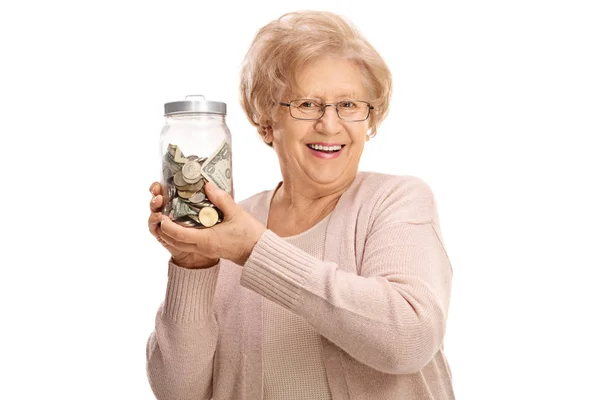 Зріла леді тримає банку, наповнену грошима — стокове фото