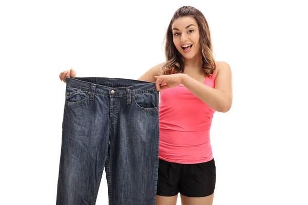 Mulher feliz segurando um par de jeans de grandes dimensões — Fotografia de Stock