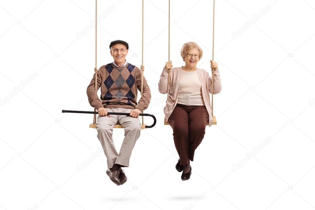 Elderly man and an elderly woman sitting on swings