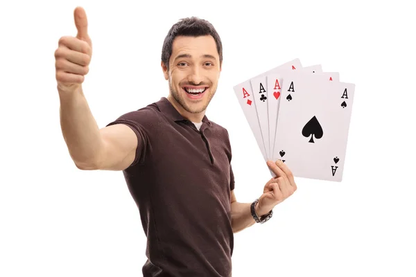 Joyful guy making a thumb up sign and holding four aces — Stock Photo, Image