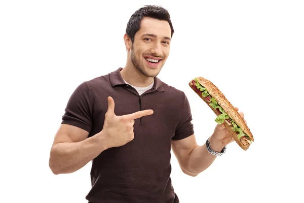 Joven sosteniendo un sándwich y señalando — Foto de Stock