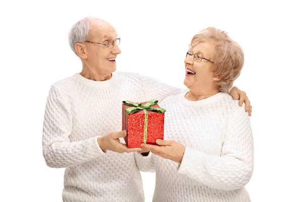 Cheerful elderly couple exchanging gifts — Stock Photo, Image