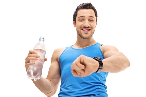 Sportler hält eine Flasche Wasser in der Hand und schaut auf seine Uhr — Stockfoto