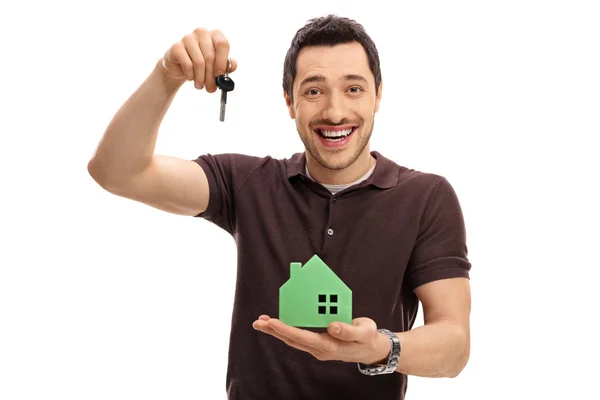 Joyful guy holding a key and a model house — Stock Photo, Image