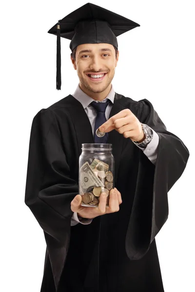 Estudiante graduado poniendo una moneda en un frasco — Foto de Stock