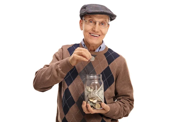 Пожилой человек кладет монету в банку с деньгами — стоковое фото