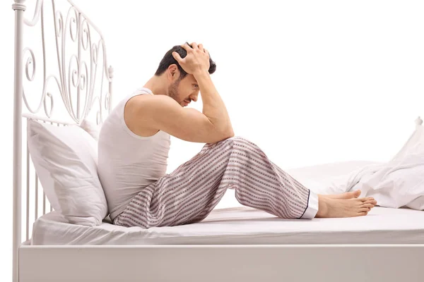 Депрессивный мужчина сидит на кровати с опущенной головой — стоковое фото