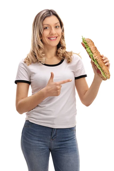 Радісна жінка тримає сендвіч і вказує — стокове фото