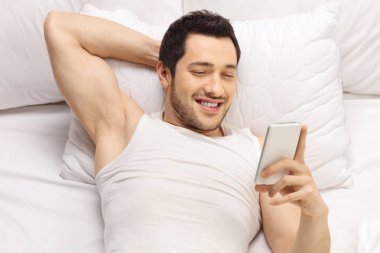 Yastığın üzerinde yalan ve telefon arayan adam