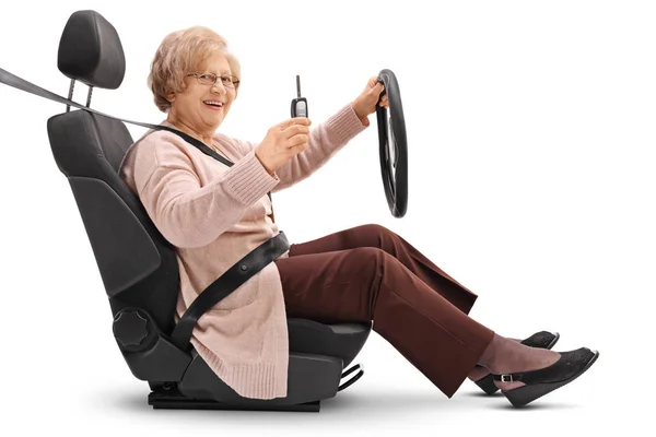 Elderly woman holding car key and sitting in car seat — Stock Photo, Image