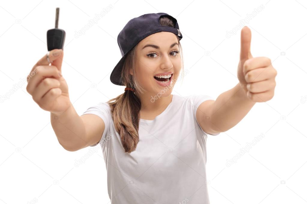 Overjoyed teenage girl holding car key and thumb up