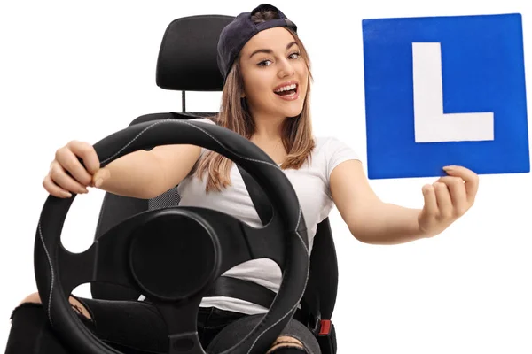Девушка показывает L-знак и сидит в автомобильном кресле — стоковое фото