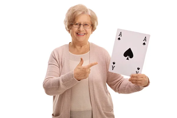 Mature lady holding an ace of spades card and pointing — Stock Photo, Image