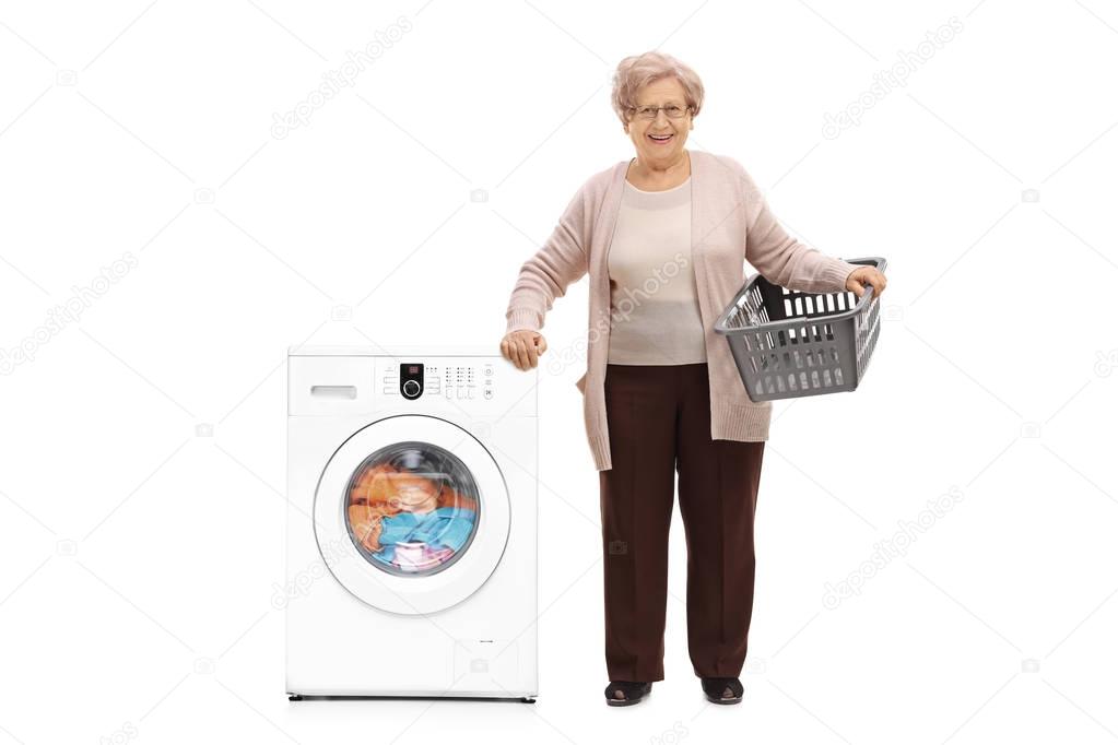 Elderly woman standing next to a washing machine