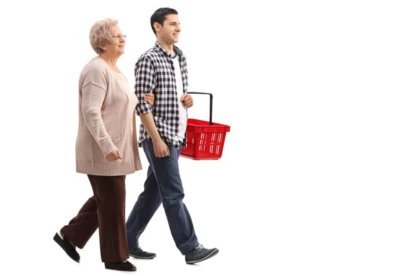 Hombre sosteniendo cesta de la compra y caminando con mujer madura —  Fotos de Stock