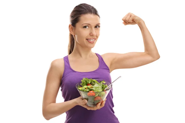 Mujer sosteniendo una ensalada y flexionando sus bíceps —  Fotos de Stock