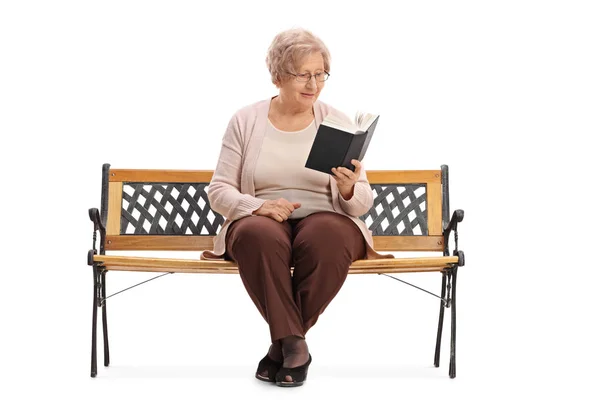 Senior zittend op een bankje en lezen van een boek — Stockfoto