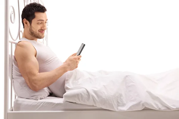 Man met behulp van een telefoon terwijl liggend in bed — Stockfoto